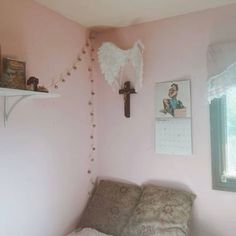 a bedroom with pink walls and a cross hanging on the wall next to a bed