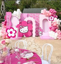 a hello kitty themed birthday party with balloons and tableware set up in front of it