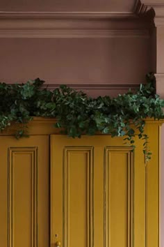 a yellow door with green plants growing on it's side and below the doors