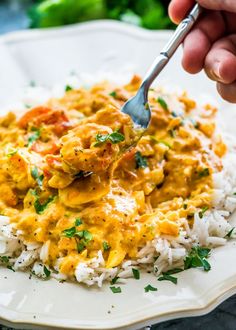 a person is spooning some food out of a white bowl on top of rice