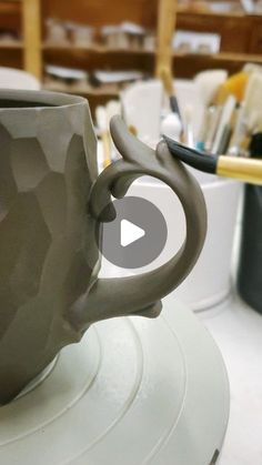 a coffee cup sitting on top of a white plate next to paintbrushes and brushes