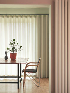 a dining table with two chairs and a potted plant on it in front of a window