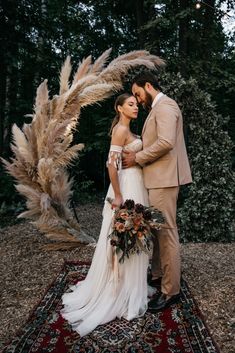 a bride and groom are standing in front of an arch with pamodia flowers