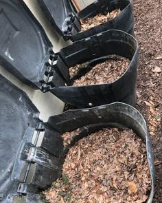 there are three black plastic buckets filled with mulch