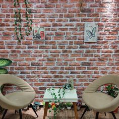 two chairs and a table in front of a brick wall with plants growing on it