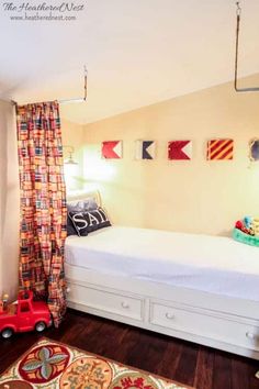 a child's bedroom with a bed, dresser and toy car on the floor