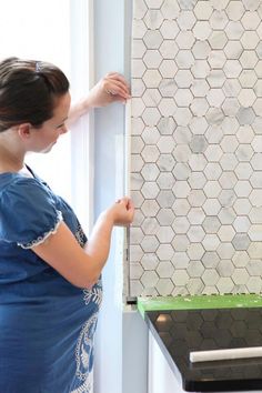 a woman is working on a tile wall