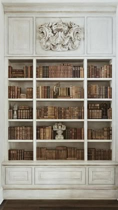 an old white bookcase with many books on the top and bottom shelves in front of it