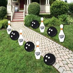 bowling pins are lined up in front of a house with yard decorations on the lawn