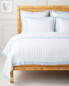 a white bed with blue trim and pillows