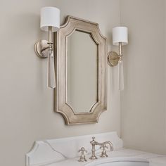 a bathroom sink sitting under a mirror next to a wall mounted faucet with two lights on it