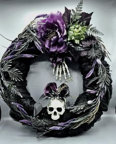 a wreath decorated with purple flowers and skeleton bones is displayed in front of a gray background