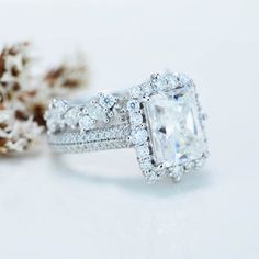 an engagement ring with a princess cut diamond surrounded by pave diamonds and white gold