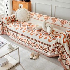 an orange and white blanket sitting on top of a bed next to a pair of slippers