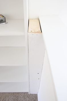 an empty white shelf next to a wall with a small object on top of it