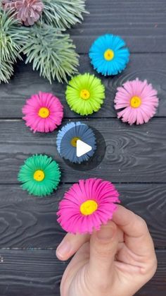 someone is holding some paper flowers in front of the camera and pointing at them with their fingers