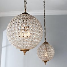 two chandeliers hanging from chains in a room