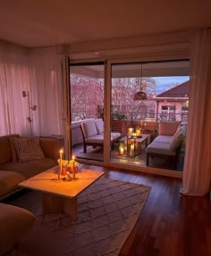 a living room with candles lit on the coffee table in front of sliding glass doors