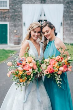 two bridesmaids pose with their bouquets in front of the barn