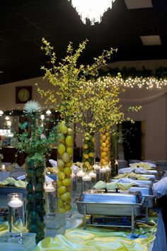 there are many vases with flowers and fruit in them on the table at this party