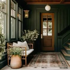 an entryway with green walls and wooden steps leading up to the front door, potted plants on either side