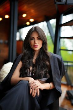 a woman sitting in a chair with her arms crossed and looking off to the side