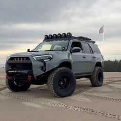 a grey four - doored toyota truck is parked in the sand on a cloudy day