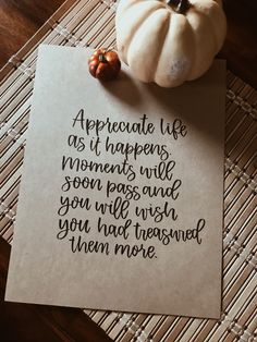 a piece of paper that has writing on it next to a small pumpkin and some leaves