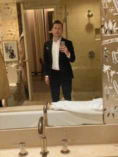 a man standing in front of a bathroom mirror taking a selfie with his cell phone