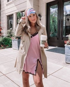 a woman in a pink dress and coat holding a cup