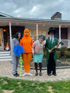 three people dressed up in halloween costumes standing on the front lawn of a house, one holding a broom