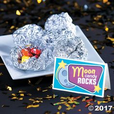 a white plate topped with foil covered donuts next to a sign that says moon candy rocks