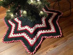 a crocheted christmas tree skirt is on the floor next to a fir tree