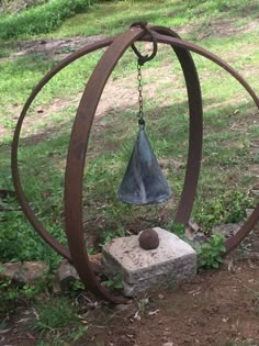 a metal bell sitting on top of a stone block in the middle of a field