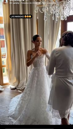 a woman in a white dress is looking at another woman's wedding dress on her phone