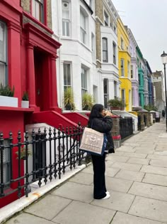 a woman standing on the sidewalk in front of colorful houses