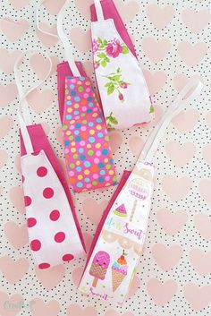 three small bags with different designs on them sitting on a polka dot tablecloth covered surface