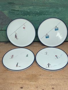 four plates with skiers on ski lift painted on them