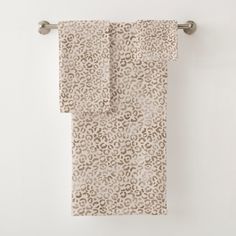 two towels hanging on a towel rack in front of a white wall with an animal print design