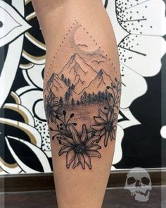 a woman's leg with flowers and mountains on it