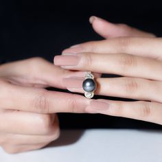 a woman's hand with a ring on her finger and a pearl in the middle