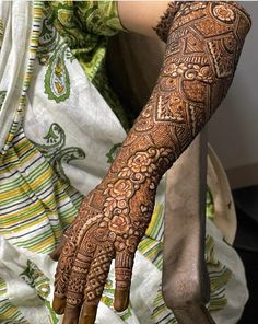 a woman's hand with henna tattoos on her arm and hands, showing the intricate