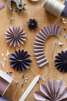 some paper flowers are on a table with scissors and spools of thread next to them