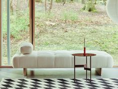 a white couch sitting in front of a window next to a black and white checkered rug