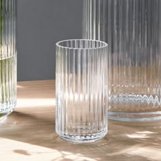 three clear vases sitting on top of a wooden table next to eachother