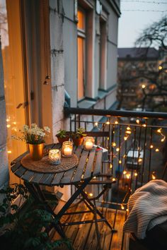 Cozy balcony decorated with string lights, candles, and plants, creating a warm evening atmosphere. London Balcony Ideas, Small Deck Decorating Ideas Cozy, Window To Balcony, Extra Small Balcony Ideas, Small Square Balcony Ideas, Tiny Apartment Balcony Ideas, Summer Balcony Aesthetic, Balcony Winter Ideas