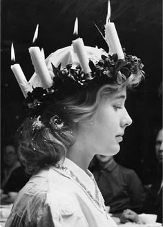 black and white photograph of a woman with candles on her head