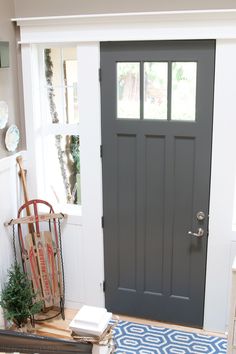 the front door is painted gray and has a blue rug on the floor next to it