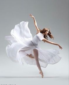 a woman in white is dancing on a gray background