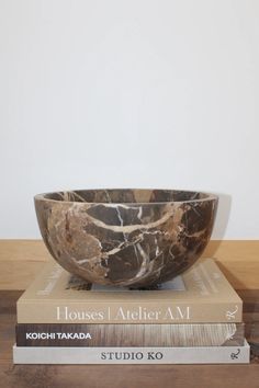 two books stacked on top of each other next to a black and white marble bowl